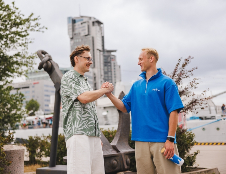 Bezpieczeństwo wewnętrzne | Studia I stopnia w Gdyni | Uniwersytet WSB Merito Gdynia: Studenci wymieniają sobie uścisk dłoni przy Sea Tower w Gdyni