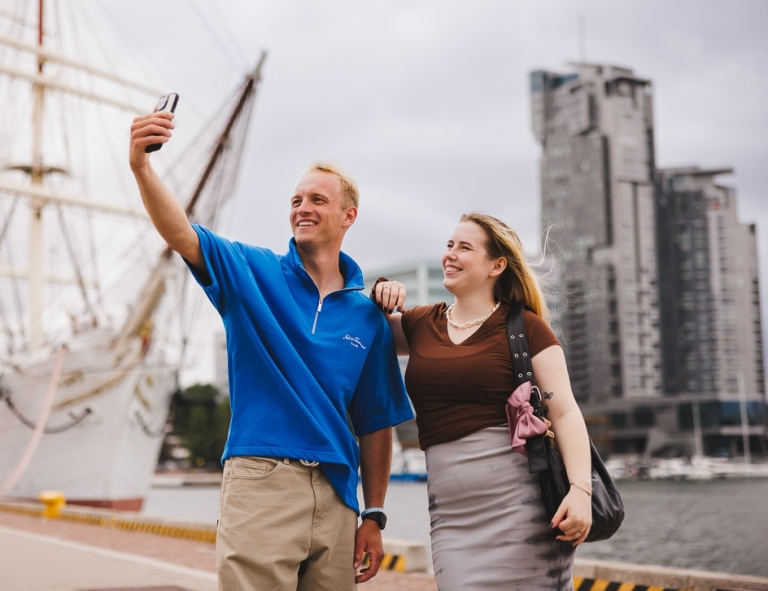 Turystyka żeglarska i sporty motorowodne | Studia I stopnia w Gdyni | Uniwersytet WSB Merito Gdynia: Para studentów robi sobie selfie na tle Sea Tower w Gdyni