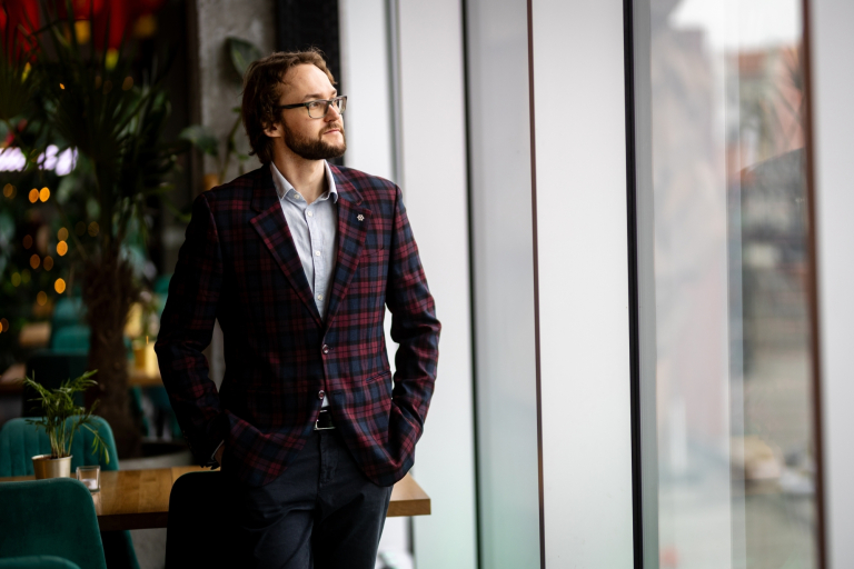 Analityk finansowy | Studia podyplomowe w Gdyni | Uniwersytet WSB Merito Gdynia: Student przy oknie w garniturze