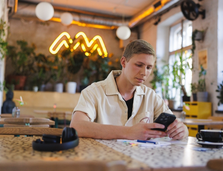 Kadry i płace | Studia I stopnia w Gdyni | Uniwersytet WSB Merito Gdynia: Student w kawiarni przy komórce