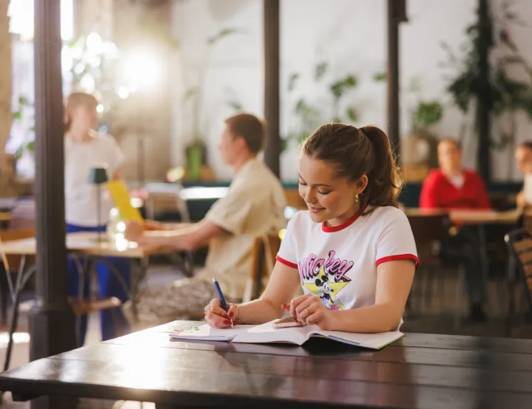Kadry i płace | Studia I stopnia w Gdyni | Uniwersytet WSB Merito Gdynia: Studentka w kawiarni przy notatkach
