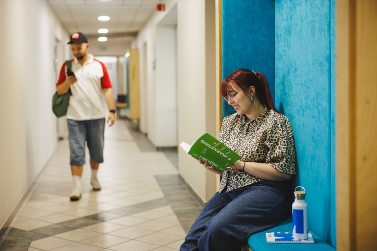 Psychologia skutecznej sprzedaży | Studia podyplomowe w Gdyni | Uniwersytet WSB Merito Gdynia: Student idzie przez korytarz w budynku Uniwersytetu w Gdyni