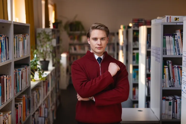 Dni otwarte Wydziałów | Uniwersytet WSB Merito Gdynia: Student w bibliotece w swetrze, a pod spodem w koszuli