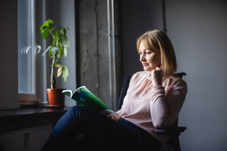 Sustainability & Business Strategy. Strategiczne zarządzanie zrównoważonym rozwojem z certyfikatem Corporate Sustainability Manager. | Studia podyplomowe w Gdyni | Uniwersytet WSB Merito Gdynia: Słuchaczka siedząca przy oknie i czytająca gazetę 