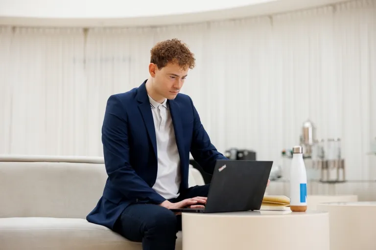 Energetyka wiatrowa | Studia podyplomowe w Gdyni | Uniwersytet WSB Merito Gdynia: Mężczyzna w garniturze przy laptopie w jasnej przestrzeni