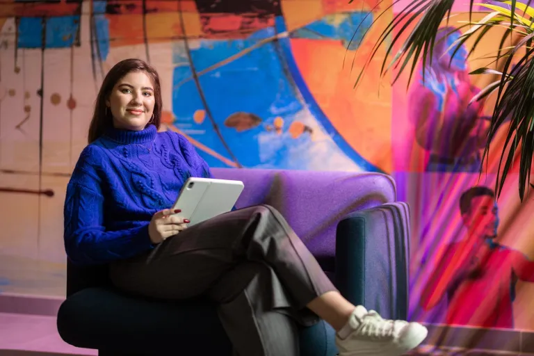 Studentka siedzi na fotelu z tabletem w tle kolorowa fototapeta