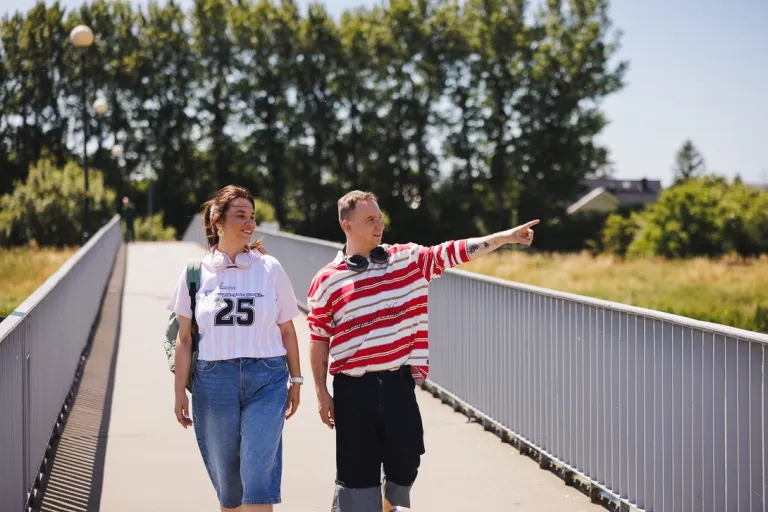 Studenci idą mostem, chłopak pokazuje dziewczynie coś w dali