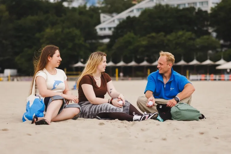 Studenci siedzą na piasku na plaży