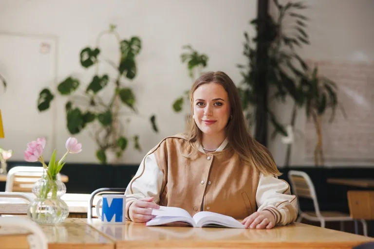 Filologia | Studia I stopnia w Gdyni | Uniwersytet WSB Merito Gdynia: Studentka przy stoliku z książką i kubkiem