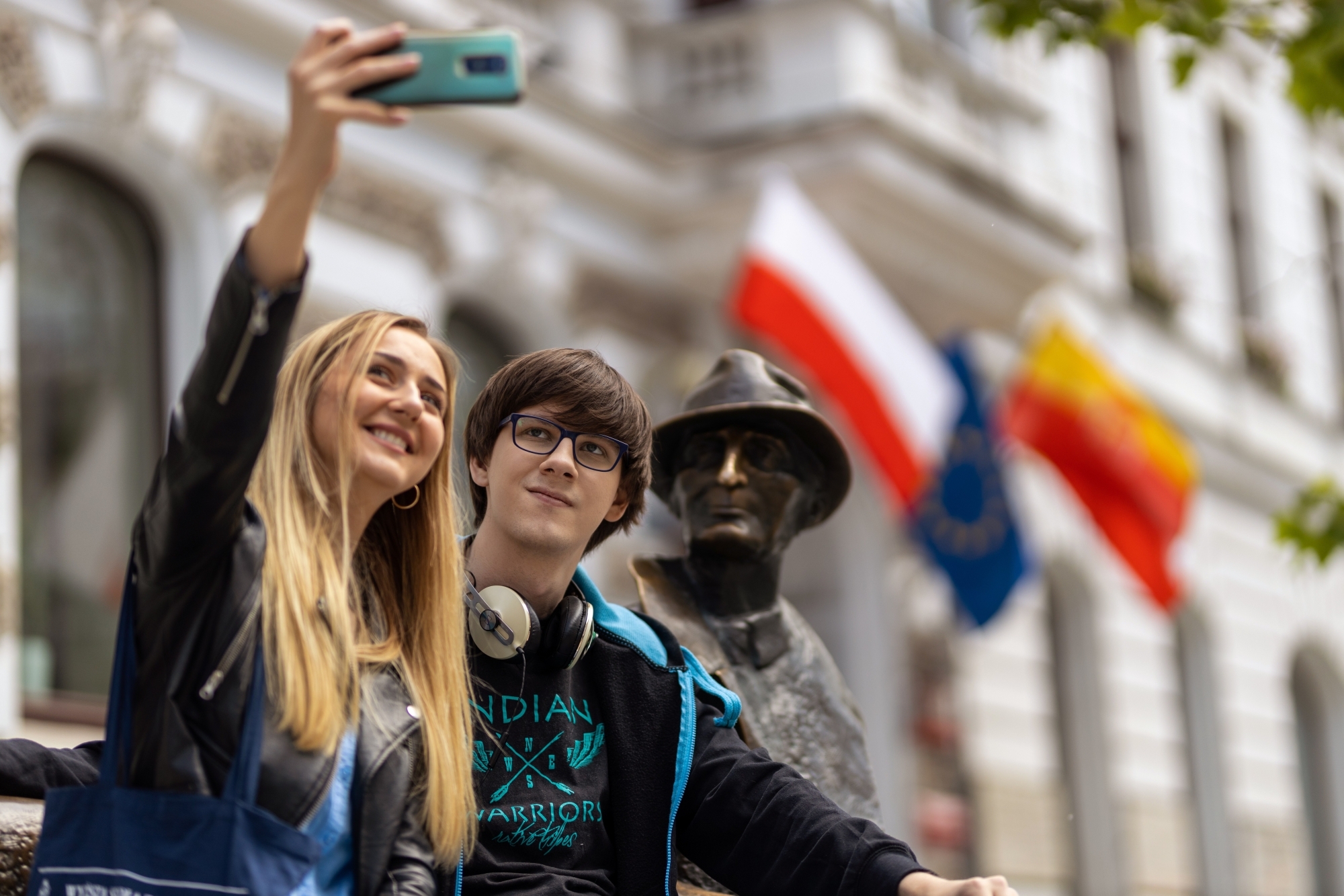 Dwoje młodych ludzi robiący selfie z statuą