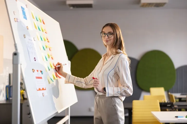 Co dają studia podyplomowe? 5 często zadawanych pytań o podyplomówkę | Uniwersytet WSB Merito: Grafika_główna_kobieta_pisząca_na_tablicy