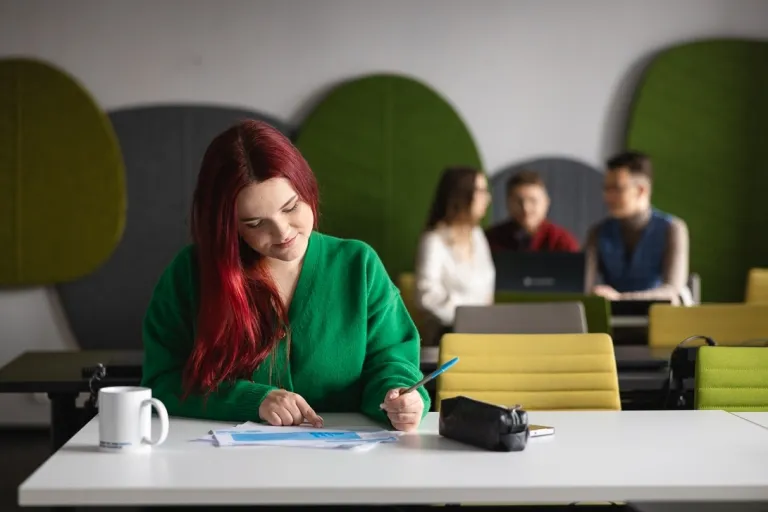 Jakie studia wybrać? | Uniwersytet WSB Merito: Grafika_główna_kobieta_pisząca_w_zeszycie