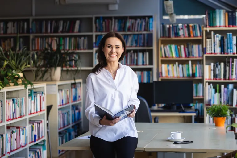 Gdzie zgłosić nieuczciwego pracodawcę? | Uniwersytet WSB Merito: Uczestniczka MBA pozuje z informatorem w bibliotece- Uniwersytet WSB Merito Toruń