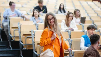 Studentka uśmiecha się do obiektywu na sali wykładowej Uniwersytetu WSB Merito w Łodzi