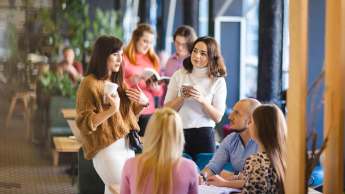 Psychologia w biznesie | Studia podyplomowe w Łodzi | Uniwersytet WSB Merito Łódź: Grupa ludzi rozmawia przy stole.