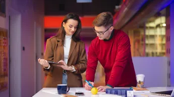 Gospodarowanie nieruchomościami | Studia I stopnia w Łodzi | Uniwersytet WSB Merito Łódź: Dwoje młodych ludzi pracuje wspólnie przy biurku.
