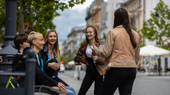 Logistyka | Studia II stopnia ze studiami podyplomowymi w Łodzi | Uniwersytet WSB Merito Łódź: Grupka studentów rozmawia śmiejąc się na mieście.