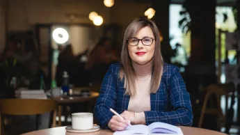 Studentka Uniwersytetu WSB Merito w Łodzi pozuje do zdjęcia.