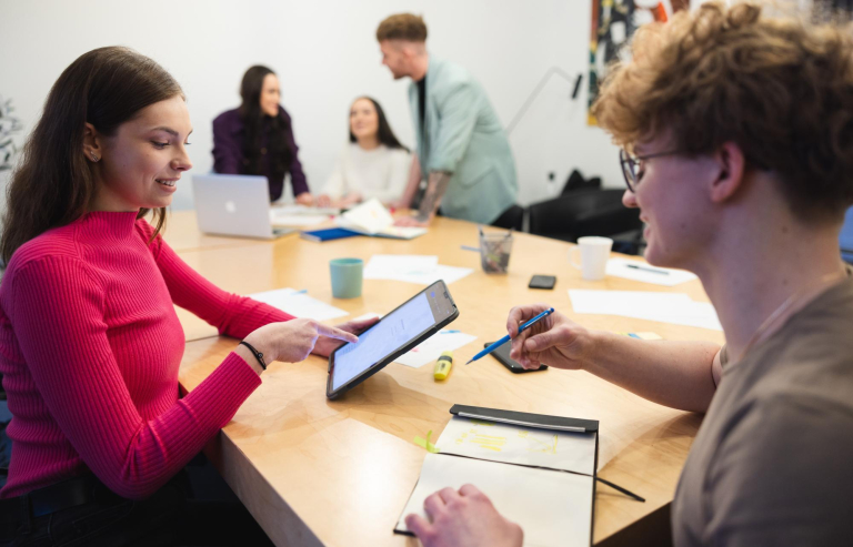 Marketing in the digital economy | Studia I stopnia w Łodzi | Uniwersytet WSB Merito Łódź: Grupa studentów siedzi przy stole i rozmawia