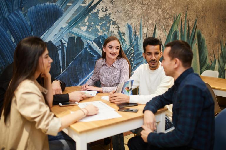 Dział Rozwoju Kształcenia Zdalnego | Uniwersytet WSB Merito Łódź: Studenci Uniwersytetu WSB Merito w Łodzi dyskutują przy stoliku