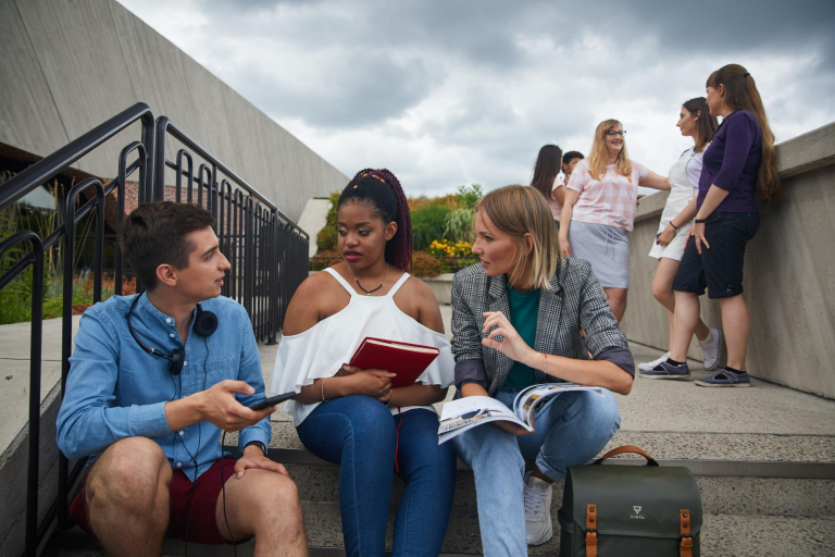 SPINAKER UWSB – Intensywne międzynarodowe programy kształcenia | Uniwersytet WSB Merito Łódź: Grupka studentów siedzi na schodach i rozmawia ze sobą