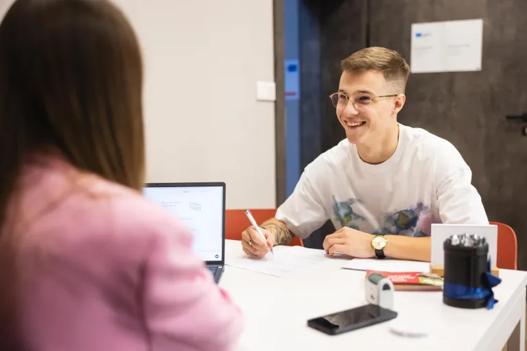 Stypendia i zniżki | Uniwersytet WSB Merito Łódź: Uczeń podpisuje dokumenty na Uniwersytecie WSB Merito