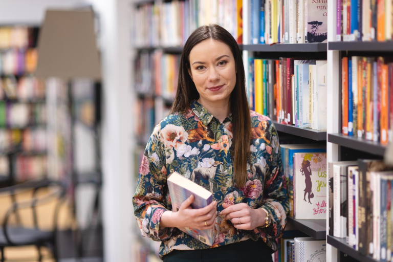 Biblioteka | Uniwersytet WSB Merito Łódź: Studentka Uniwersytetu WSB Merito pozuje do zdjęcia.