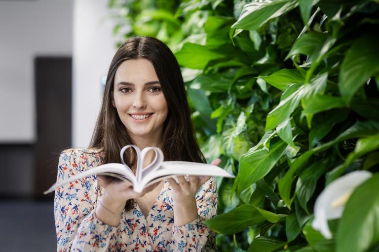 Projektowanie marki i wizerunku firmy | Studia I stopnia w Łodzi | Uniwersytet WSB Merito Łódź: Studentka Uniwersytetu WSB Merito w Łodzi pozuje z książką.