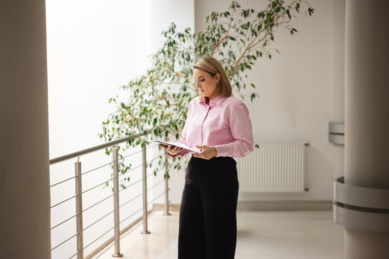 Zniżki i dofinansowania | Uniwersytet WSB Merito Łódź: kobieta stoi na korytarzu i czyta książkę 