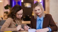 Zarządzanie w oświacie | Uniwersytet WSB Merito Opole: Główna grafika: Opole - studia podyplomowe - Zarządzanie w oświacie - Dwie kobiety przeglądające notatki