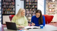 Neurodietetyka | Studia podyplomowe w Opolu | Uniwersytet WSB Merito Opole: Główna grafika-Opole- studia podyplomowe- Neurodietetyka - uczestniczki studiów podyplomowych siedzą przy biurku i piszą w notatniku