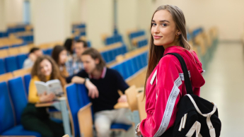 Pedagogika | Uniwersytet WSB Merito Opole: Młoda dziewczyna patrzy w obiektyw a tle widać grupę dziewcząt