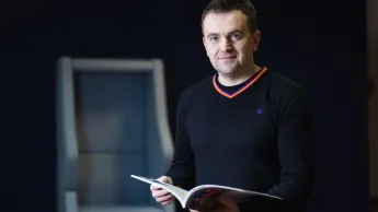 Marketing cyfrowy i grafika reklamowa | Studia I stopnia w Opolu | Uniwersytet WSB Merito Opole: Główna grafika: Opole - specjalność Marketing cyfrowy i grafika reklamowa - mężczyzna w średnim wieku z książką w dłoni