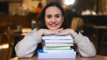 Analityka i doradztwo finansowe | Studia II stopnia w Opolu | Uniwersytet WSB Merito Opole: Główna grafika: Opole - specjalność Analityka i doradztwo finansowe  - studentka opierająca głowę o stos książek