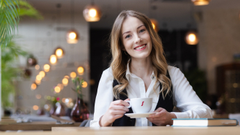 Customer experience management | Uniwersytet WSB Merito Opole: Główna grafika: Opole - studia podyplomowe - Uśmiechnięta dziewczyna z filiżanką kawy