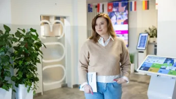 Seksuologia | Studia podyplomowe w Opolu | Uniwersytet WSB Merito Opole: Główna grafika: Opole - studia podyplomowe - Seksuologia - Kobieta trzymająca w dłoni książkę, stoi na korytarzu