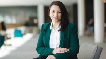 Psychologia edukacyjna | Uniwersytet WSB Merito Opole: Główna grafika: Opole - studia podyplomowe - Psychologia edukacyjna - Kobieta w kawiarni, siedzi w szarym fotelu, jest ubrana w zieloną marynarkę