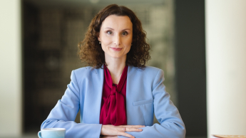 Kadry i płace | Uniwersytet WSB Merito Opole: Główna grafika: Opole - studia podyplomowe - Kadry i płace - Kobieta siedząca za biurkiem, przed nią leżą notatki