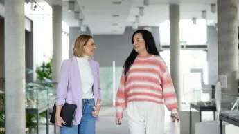 Zarządzanie zasobami ludzkimi dla menedżerów | Studia podyplomowe w Opolu | Uniwersytet WSB Merito Opole: Główna grafika: Opole - studia podyplomowe -  Zarządzanie kapitałem ludzkim - Dwie kobiety idące korytarzem