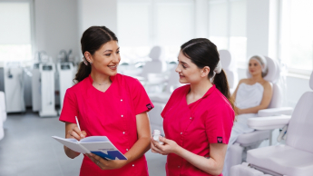 Wizaż i stylizacja z elementami charakteryzacji | Studia I stopnia w Opolu | Uniwersytet WSB Merito Opole: Główna grafika: Opole - studia I stopnia - Kosmetologia - Dwie studentki przeglądające notatki