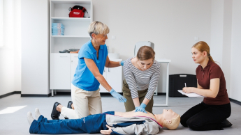 Zarządzanie kryzysowe i pomoc humanitarna | Studia II stopnia ze studiami podyplomowymi  | Uniwersytet WSB Merito Opole: Główna grafika: Opole - Studia II stopnia z podyplomowymi - specjalność Zarządzanie kryzysowe i pomoc humanitarna - Wykładowczyni pokazująca jak wykonywać pierwszą pomoc