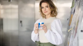 Psychodietetyka | Studia I stopnia w Opolu | Uniwersytet WSB Merito Opole: Główna grafika: Opole - studia I stopnia - specjalność psychodietetyka - Kobieta trzymająca kubek z logotypem Uniwersytetu WSB Merito