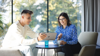 Doradztwo podatkowe | Studia II stopnia ze studiami podyplomowymi  | Uniwersytet WSB Merito Opole: Główna grafika: Opole - studia II stopnia z podyplomowymi - specjalność Doradztwo podatkowe - Dwie osoby siedzące w szarych fotelach, patrzą w ekran tabletu