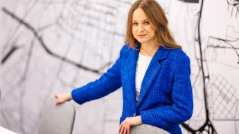 Doradztwo podatkowe | Uniwersytet WSB Merito Opole: Główna grafika: Opole - studia II stopnia - specjalność Doradztwo podatkowe - Kobieta w niebieskiej marynarce, stoi za stołem konferencyjnym