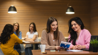 Digital marketing | Uniwersytet WSB Merito Opole: Główna grafika: Opole - studia II stopnia - specjalnosć Digital marketing - Dwie kobiety siedzące w kawiarni, przeglądają notatki