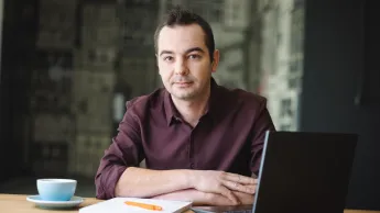 Psychospołeczne oraz prawne aspekty kryminologii i wiktymologii | Studia podyplomowe w Opolu | Uniwersytet WSB Merito Opole: Główna grafika: Opole - studia podyplomowe -Psychospołeczne oraz prawne aspekty kryminologii i wiktymologii- uczestnik studiów podyplomowych siedzi przy biurku z laptopem