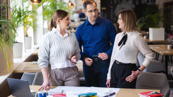 Analiza i informatyka śledcza | Uniwersytet WSB Merito Opole: Główna grafika: Opole - studia podyplomowe - Analiza i informatyka śledcza- uczestnicy studiów podyplomowych stoją przy biurku i rozmawiają