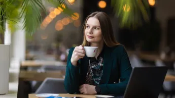 Psychodietetyka  dzieci i młodzieży | Uniwersytet WSB Merito Opole: Główna grafika: Opole - studia podyplomowe -Psychodietetyka dzieci i młodzieży - uczestniczka studiów podyplomowych siedzi przy biurku z filiżanką w ręce i spogląda za okno