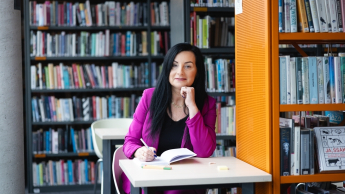 Warsztat pracy pedagoga-wychowawcy | Studia podyplomowe w Opolu | Uniwersytet WSB Merito Opole: Główna grafika: Opole - studia podyplomowe -Warsztat pracy pedagoga-wychowawcy- uczestniczka studiów podyplomowych siedzi przy stoliku i robi notatki