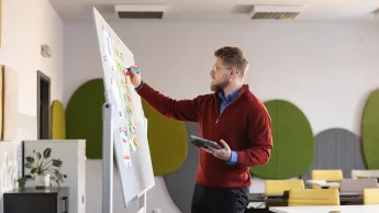 Zarządzanie zasobami ludzkimi | Uniwersytet WSB Merito Opole: Główna grafika: Opole - studia I stopnia licencjackie - Zarządzanie: Zarządzanie zasobami ludzkimi - student robi notatki na flipcharcie